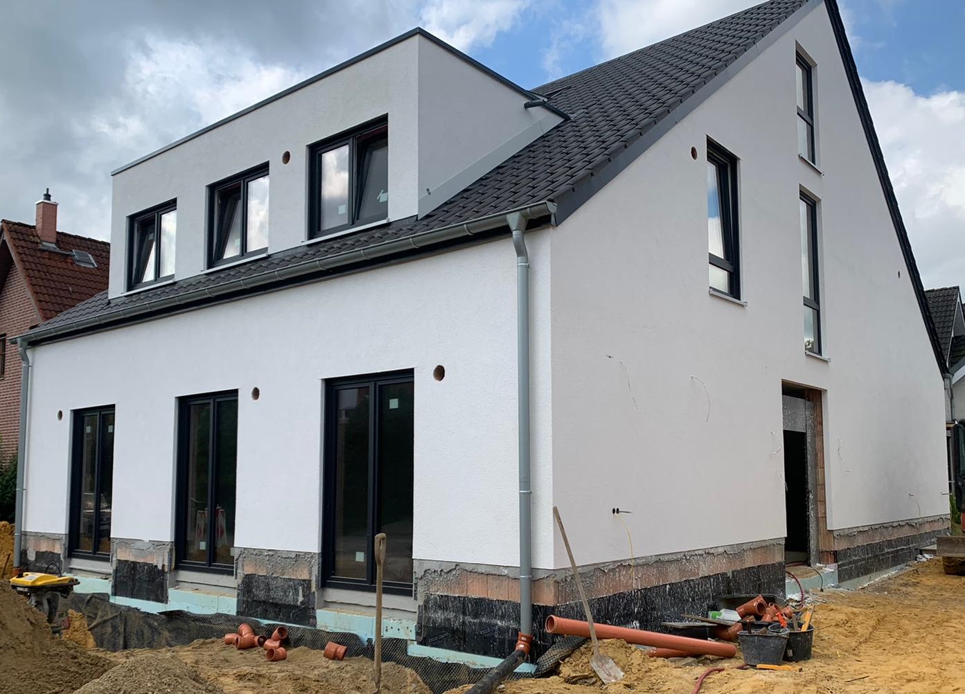 Außenansicht Fassade (Hochlochziegel verputzt) mit Gaube des Neubaus von drei Mehrfamilienhäusern in Münster (NRW)